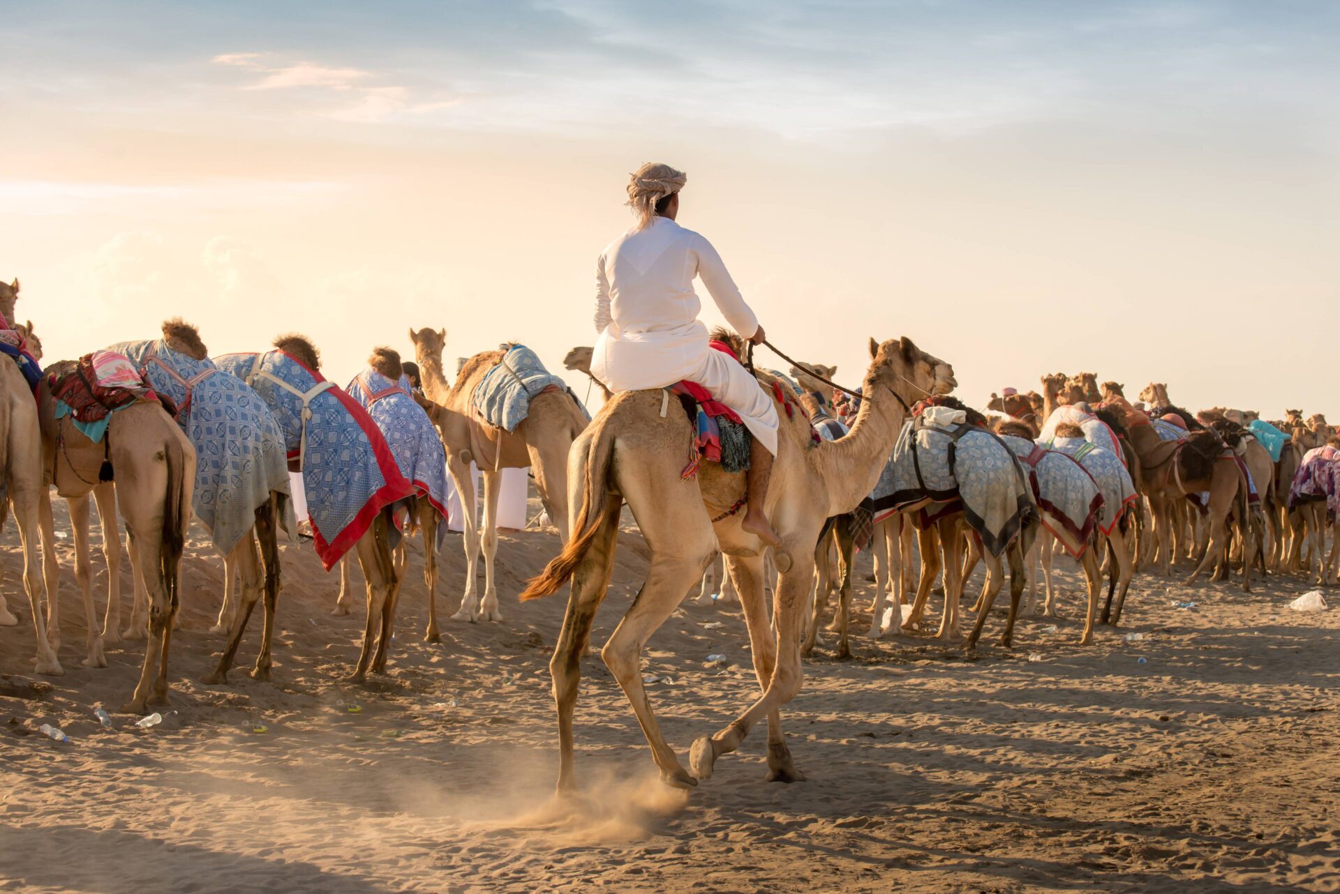 4x4 vehicle with roof-top tent parked in the Omani desert at sunset with high sand dunes in the background