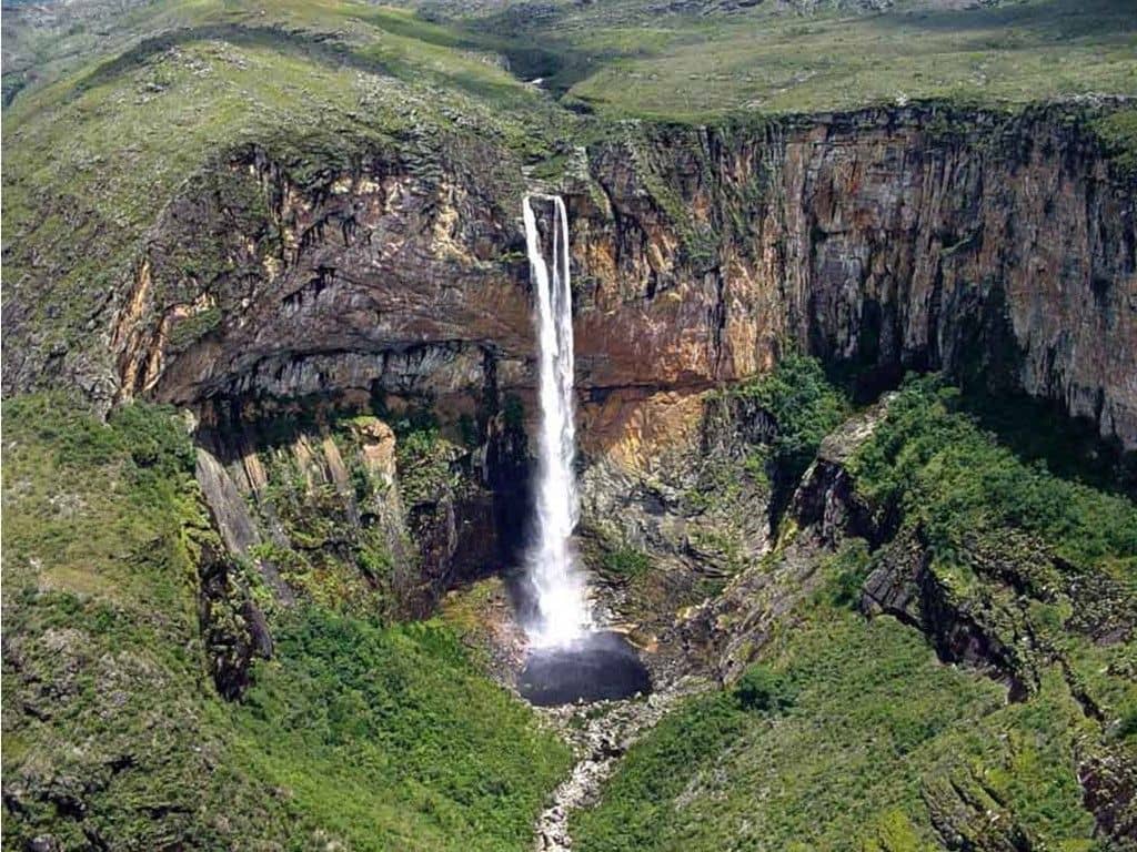 A deep canyon and the vertical drop of Cachoeira da Fumaça waterfall viewed from a high cliff in Chapada Diamantina