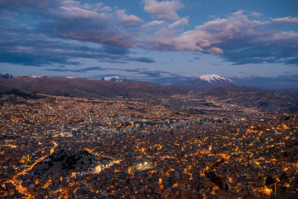 Aerial cable cars gliding over the densely built valley of La Paz with snow-capped Illimani mountain in the background