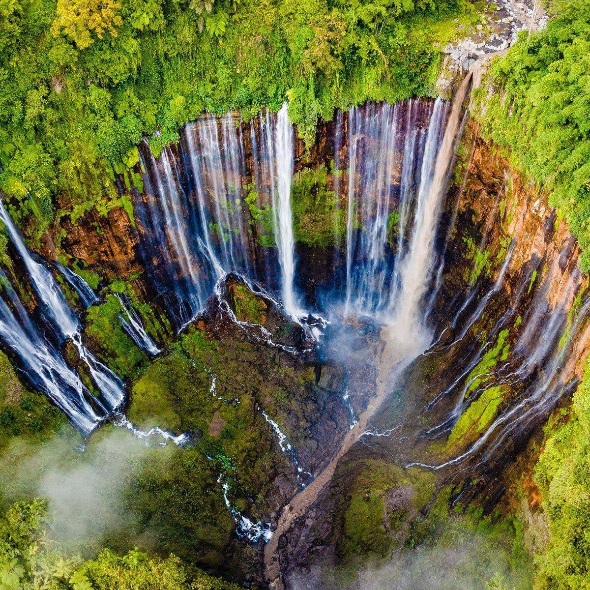 Aerial view of Tumpak Sewu waterfall plunging into a deep green canyon in East Java