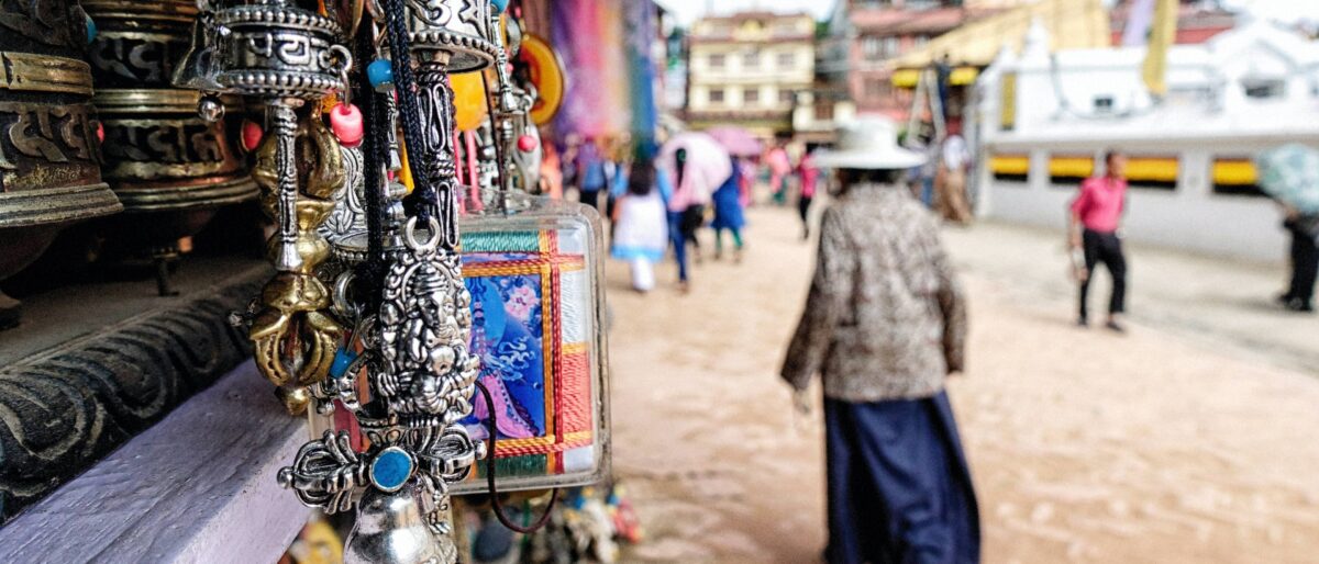 Aerial view over central Kathmandu with dense buildings and surrounding green hills under a soft sky