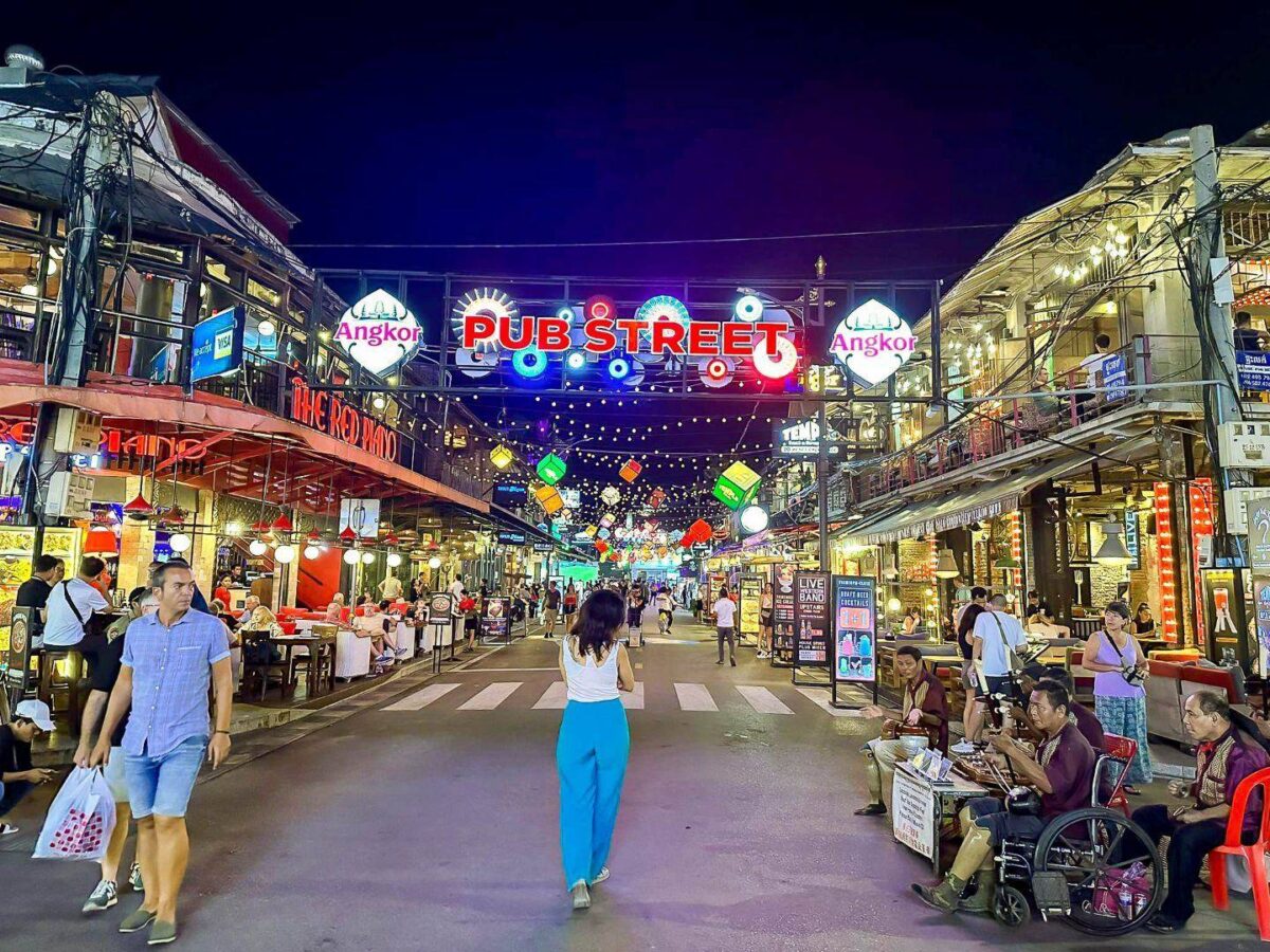 Airplane on the tarmac at Siem Reap airport with palm trees and low terminal building in the background