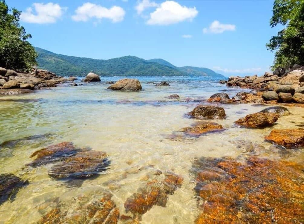 Boat approaching the forested shores and sandy beaches of Ilha Grande under a sunny sky