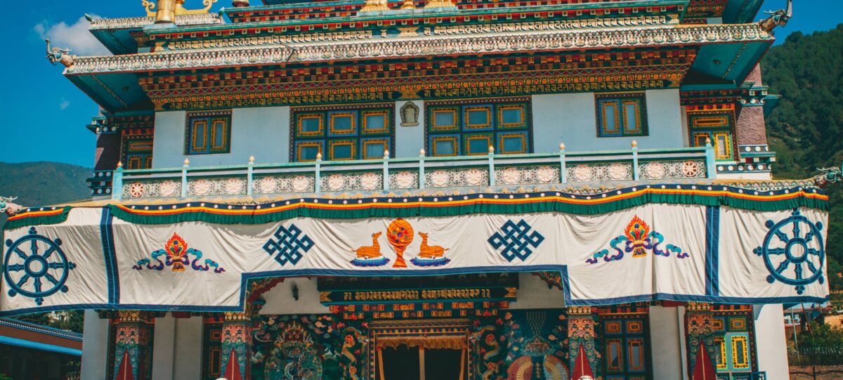 Buddhist monastery near Pharping nestled on a hillside with colorful prayer flags and forested slopes