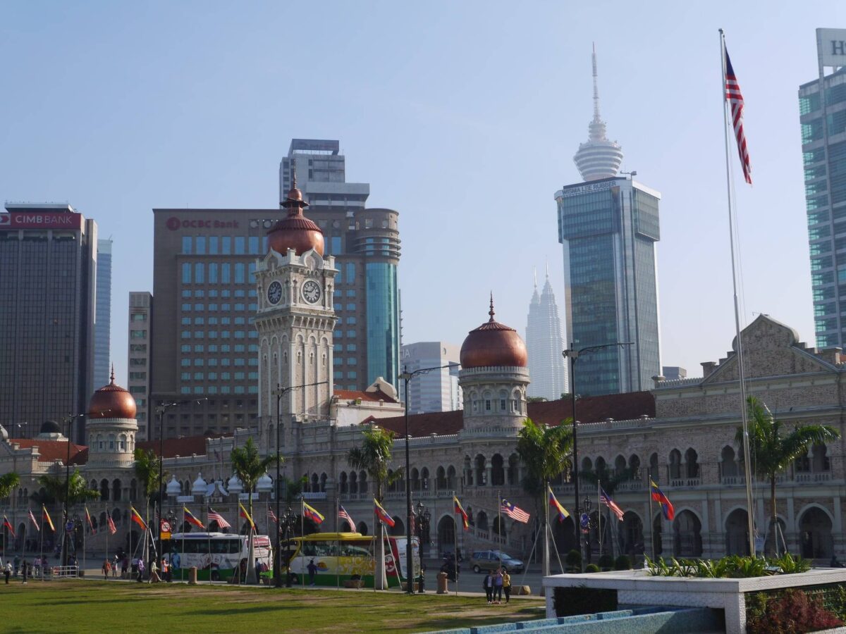 Busy street in central Kuala Lumpur with pedestrians, market stalls and modern high-rises in the background