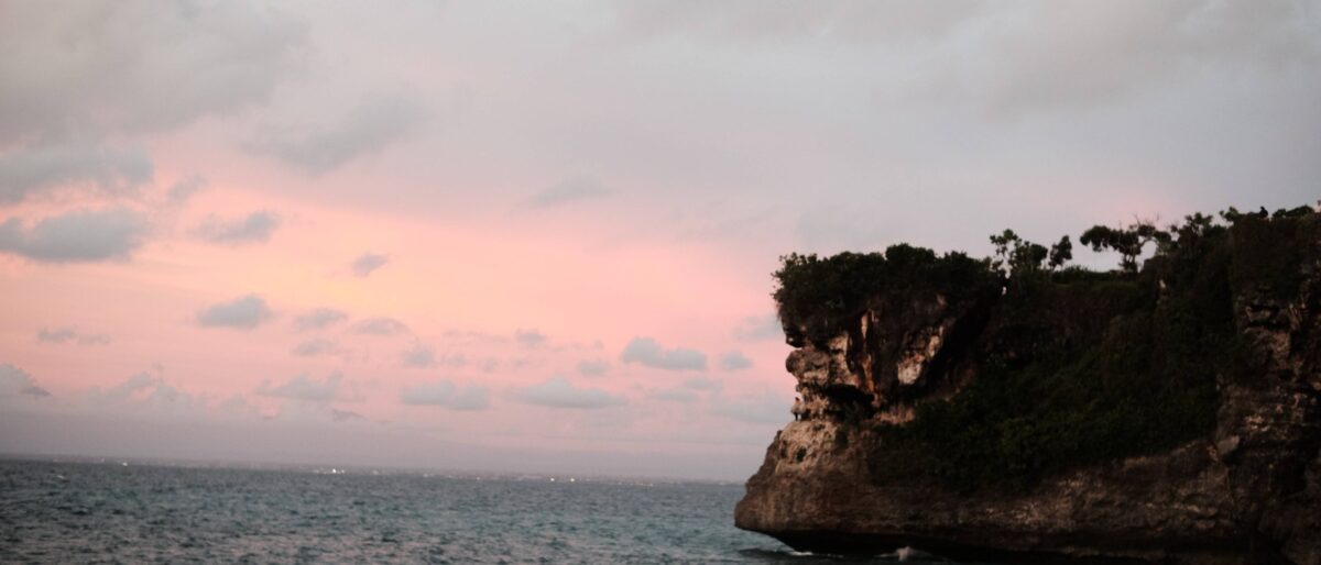 Calm sandy beach in Sanur with traditional fishing boats and gentle waves at sunrise