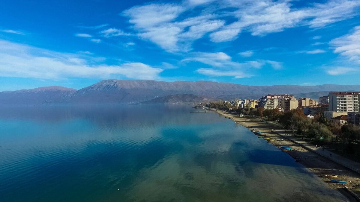 Calm waters of Lake Ohrid near Pogradec with mountains in the distance and lakeside houses