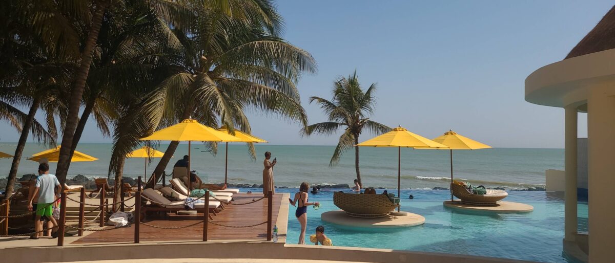 Children playing in the pool of a seaside hotel in Somone with the ocean and palm trees in the background