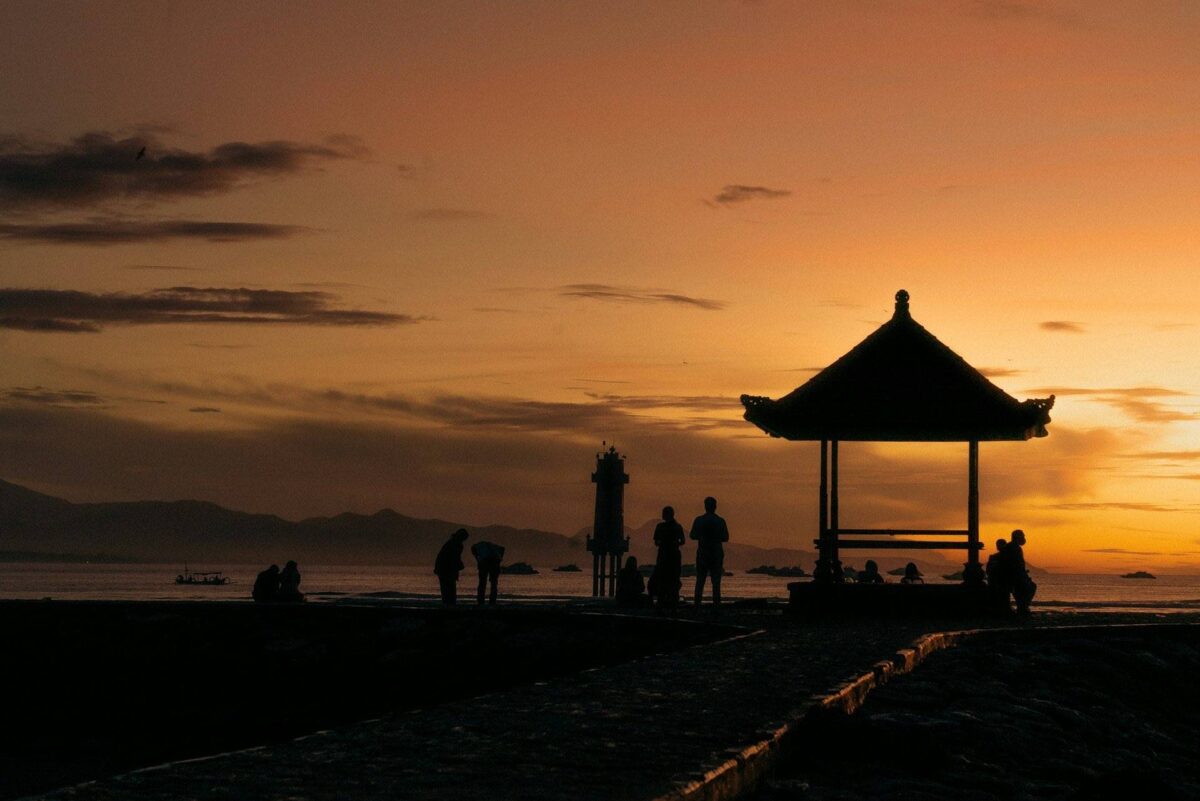Children splashing in shallow turquoise water on Sanur beach while parents relax nearby
