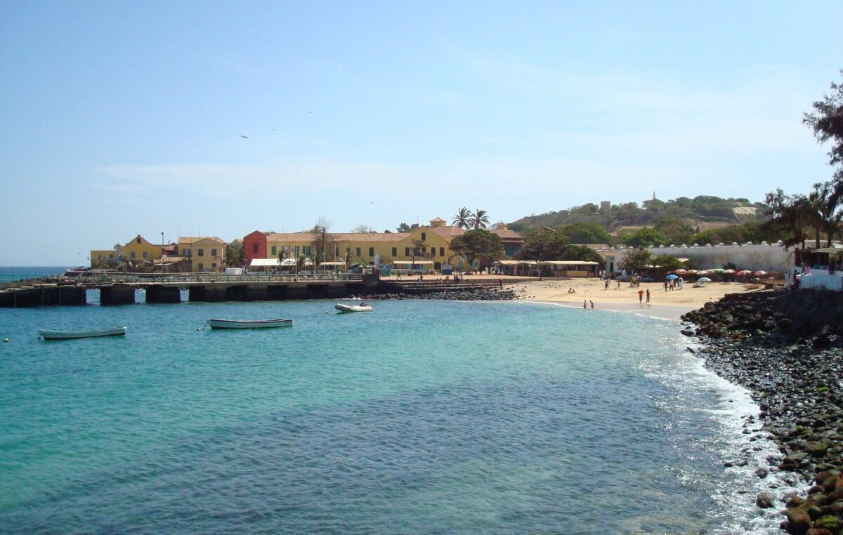 Colorful colonial houses overlooking the sea on Gorée Island near Dakar, Senegal, with a ferry approaching the pier
