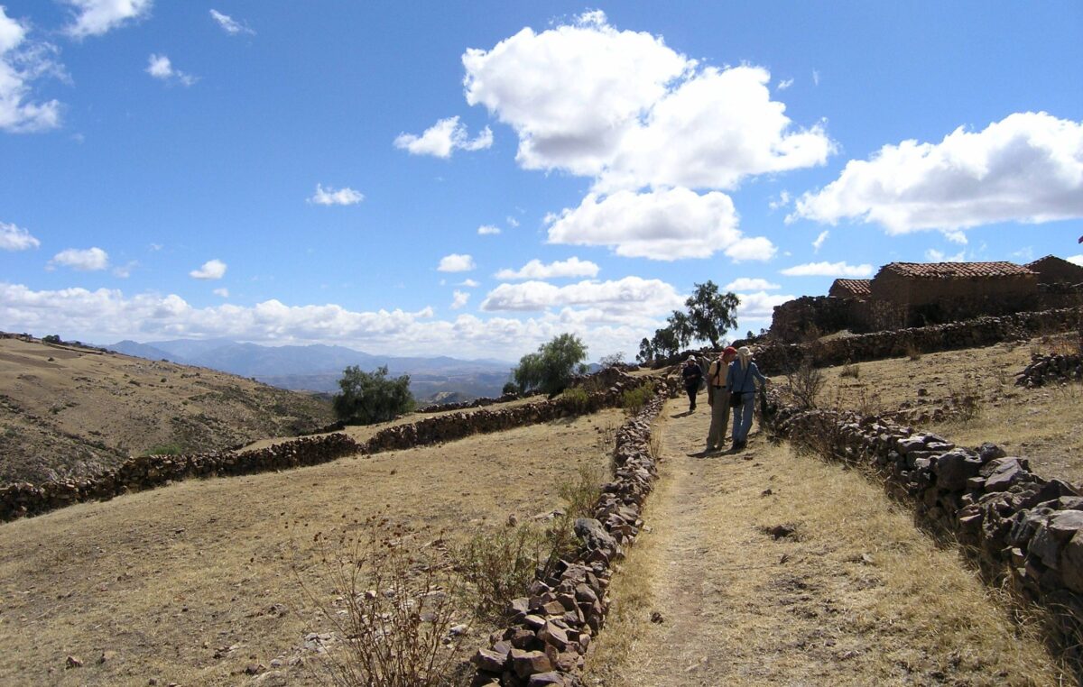 Colorful layered rock formations of the Maragua Crater with a narrow Inca trail winding through the Andean landscape
