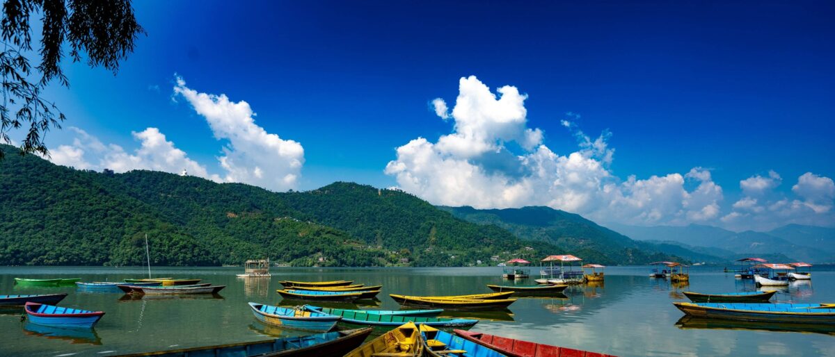 Colorful wooden boats floating on Phewa Lake in Pokhara with Annapurna mountains in the background at sunset