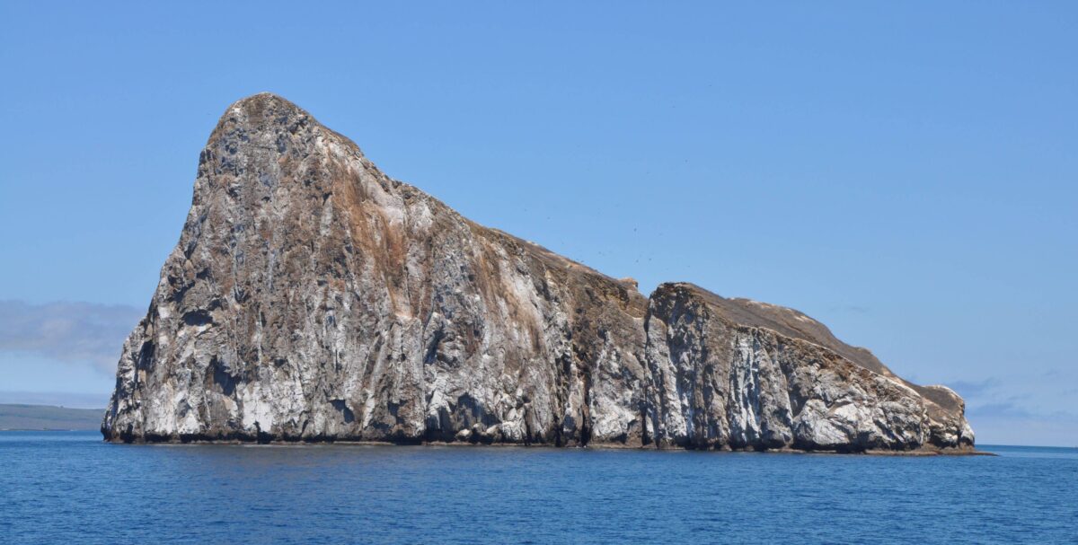 Dramatic vertical cliffs of Kicker Rock rising from deep blue ocean waters in the Galapagos Islands