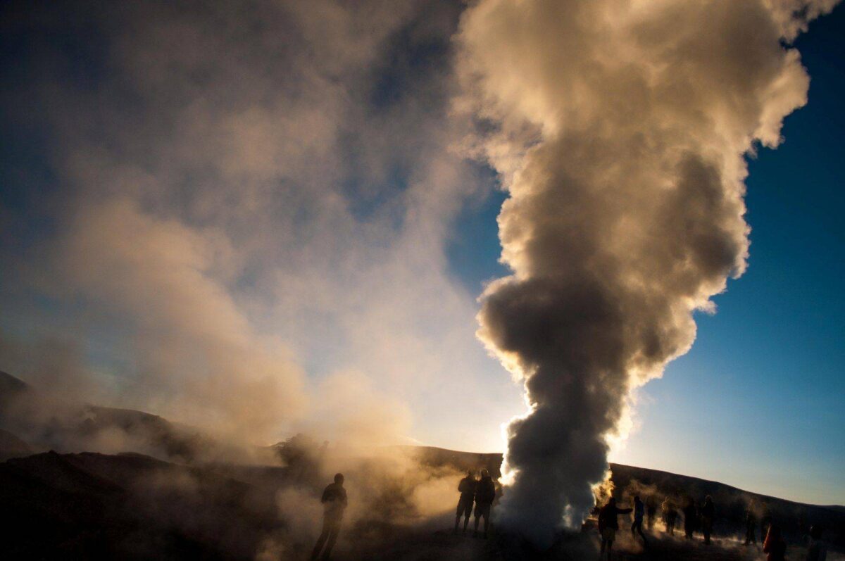 Dusty 4x4s crossing a high-altitude desert in South Lipez with the cone-shaped Licancabur volcano on the horizon