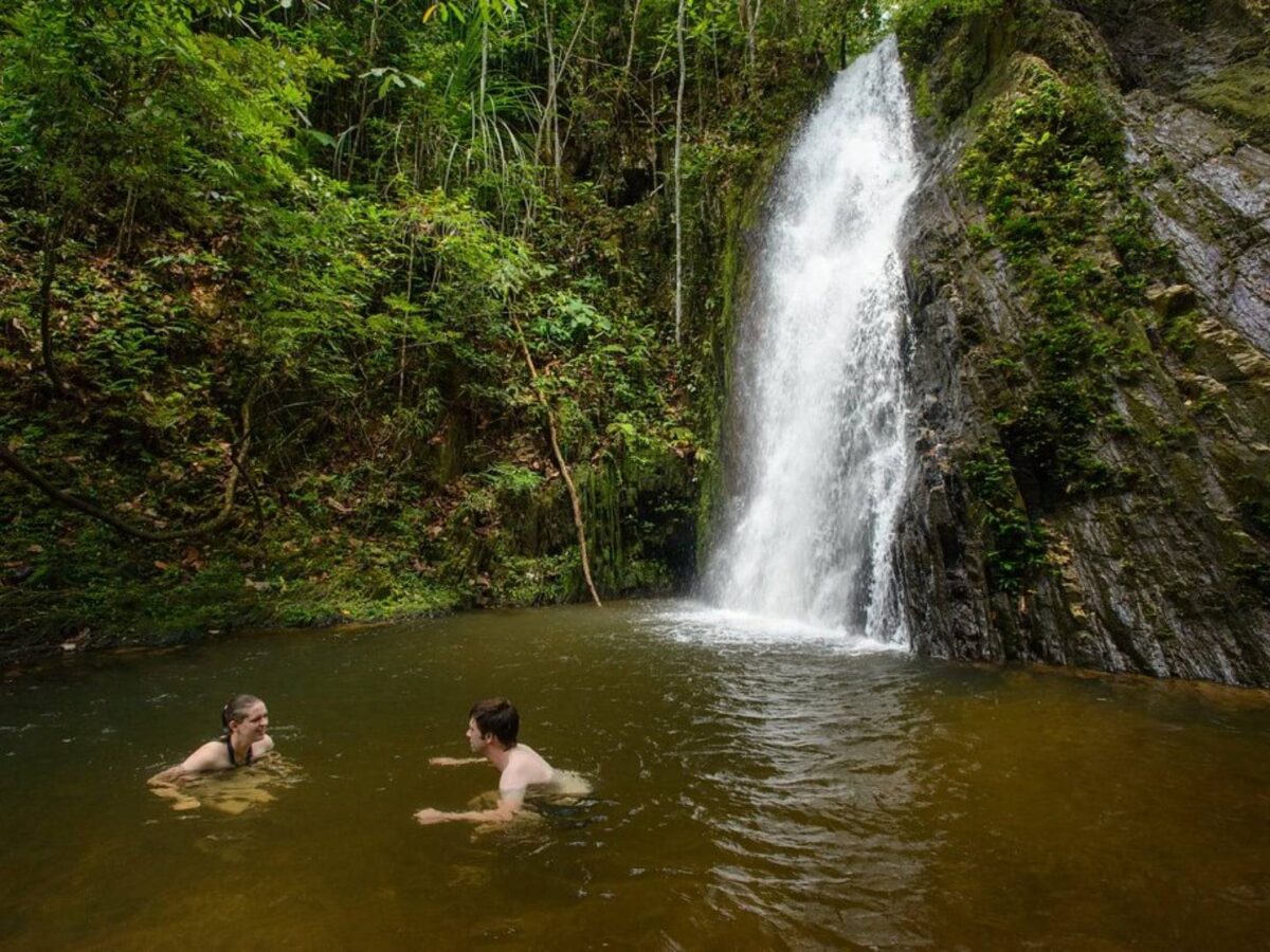 Enseluai Waterfall cascading into a natural pool surrounded by dense green rainforest in Batang Ai