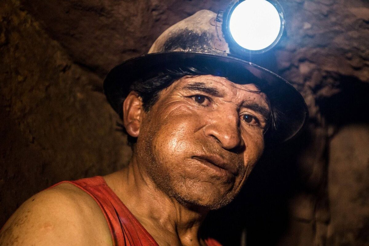 Entrance of a silver mine near Potosí with miners wearing helmets and protective gear at the tunnel mouth