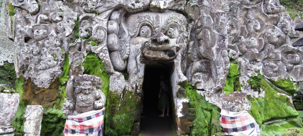 Entrance of Goa Gajah Elephant Cave temple with intricate stone carvings surrounded by jungle