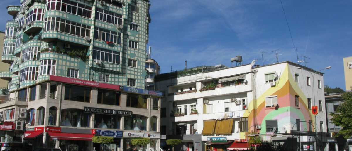 Evening view of central Tirana with illuminated buildings, wide boulevard and surrounding mountains in the distance