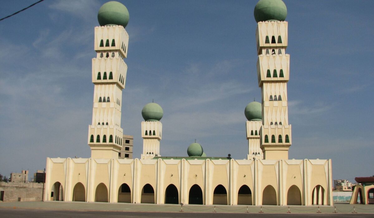 Evening view of Dakar with coastal buildings and lights along the shoreline at sunset