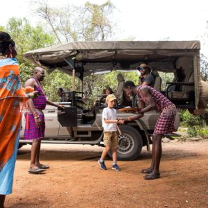 Family on safari vehicle watching giraffes and zebras in the savannah of Kenya’s Great Rift Valley at sunset