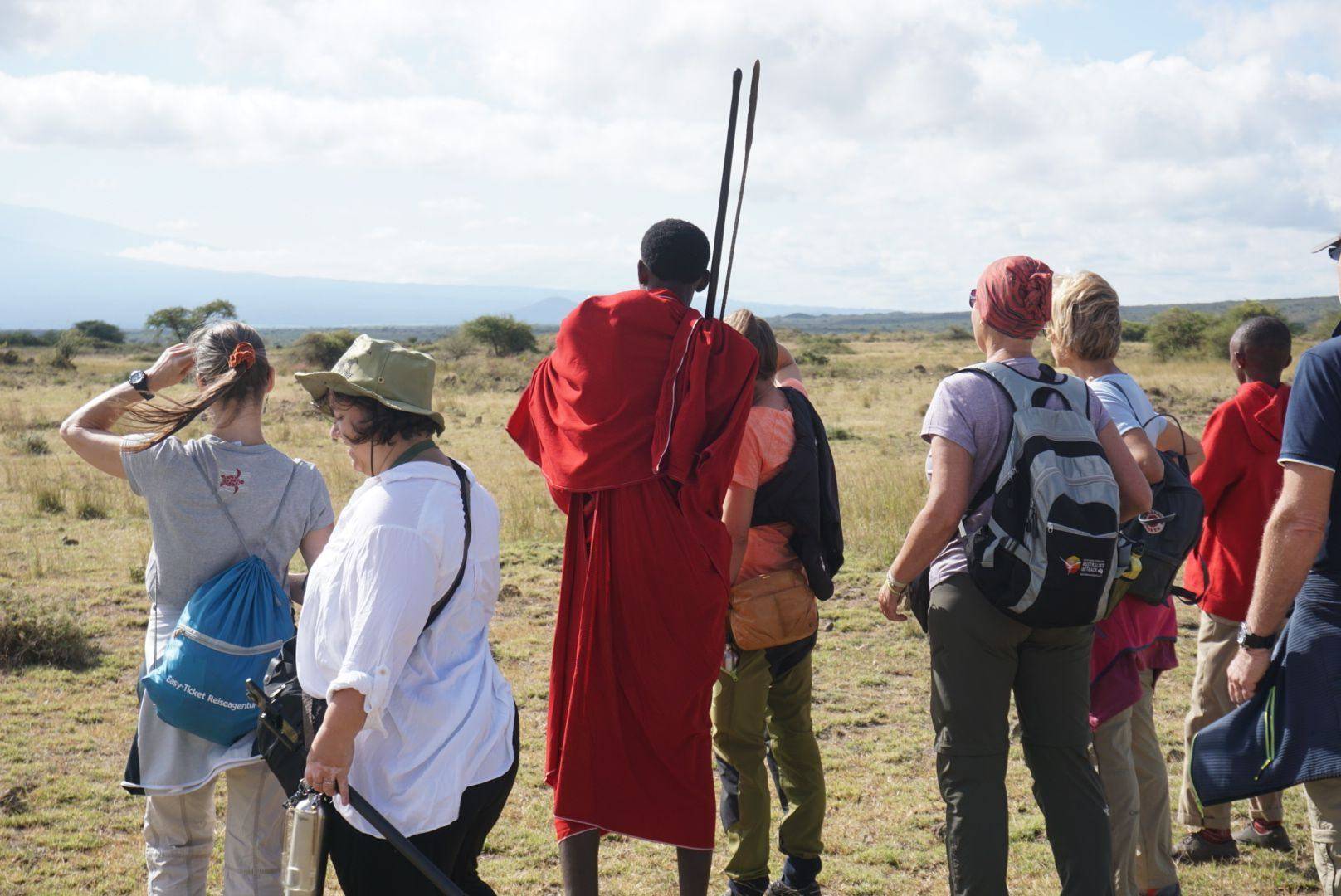 Family on safari vehicle watching giraffes on the savannah with Kilimanjaro in the background at sunset in Tanzania