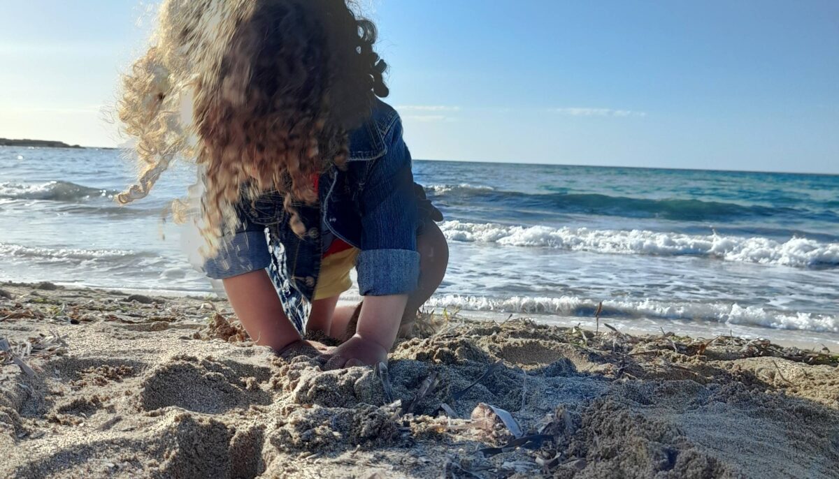 Family relaxing on a sandy beach in Djerba, Tunisia, with turquoise sea, sun loungers and children playing near the water