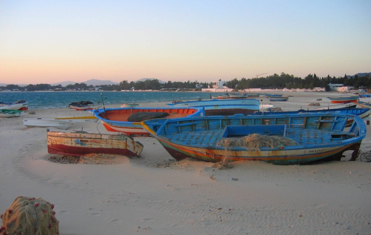 Family relaxing on sun loungers by a hotel pool overlooking the beach in Hammamet, Tunisia