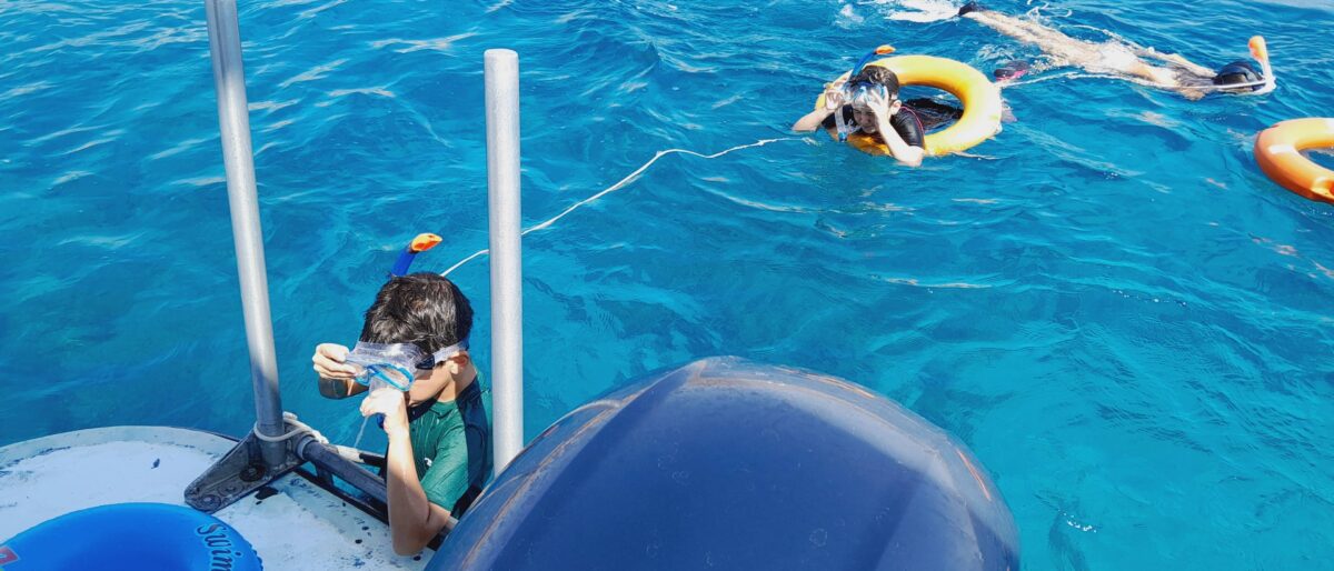 Family riding camels across the sandy plains of Wadi Rum with rocky mountains in the background