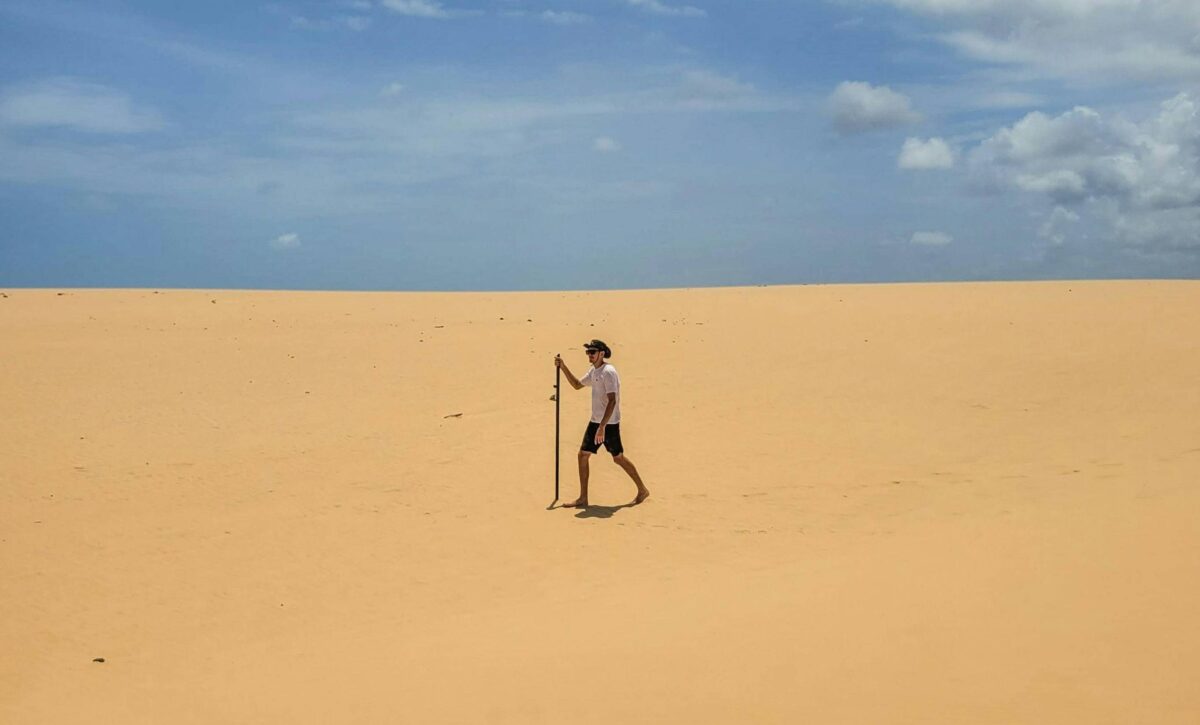 Family sandboarding down white Sahara dunes near an old desert well at Bir Boubaker