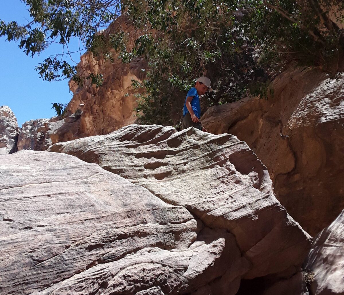 Family sitting around a campfire near rock formations in Little Petra at dusk