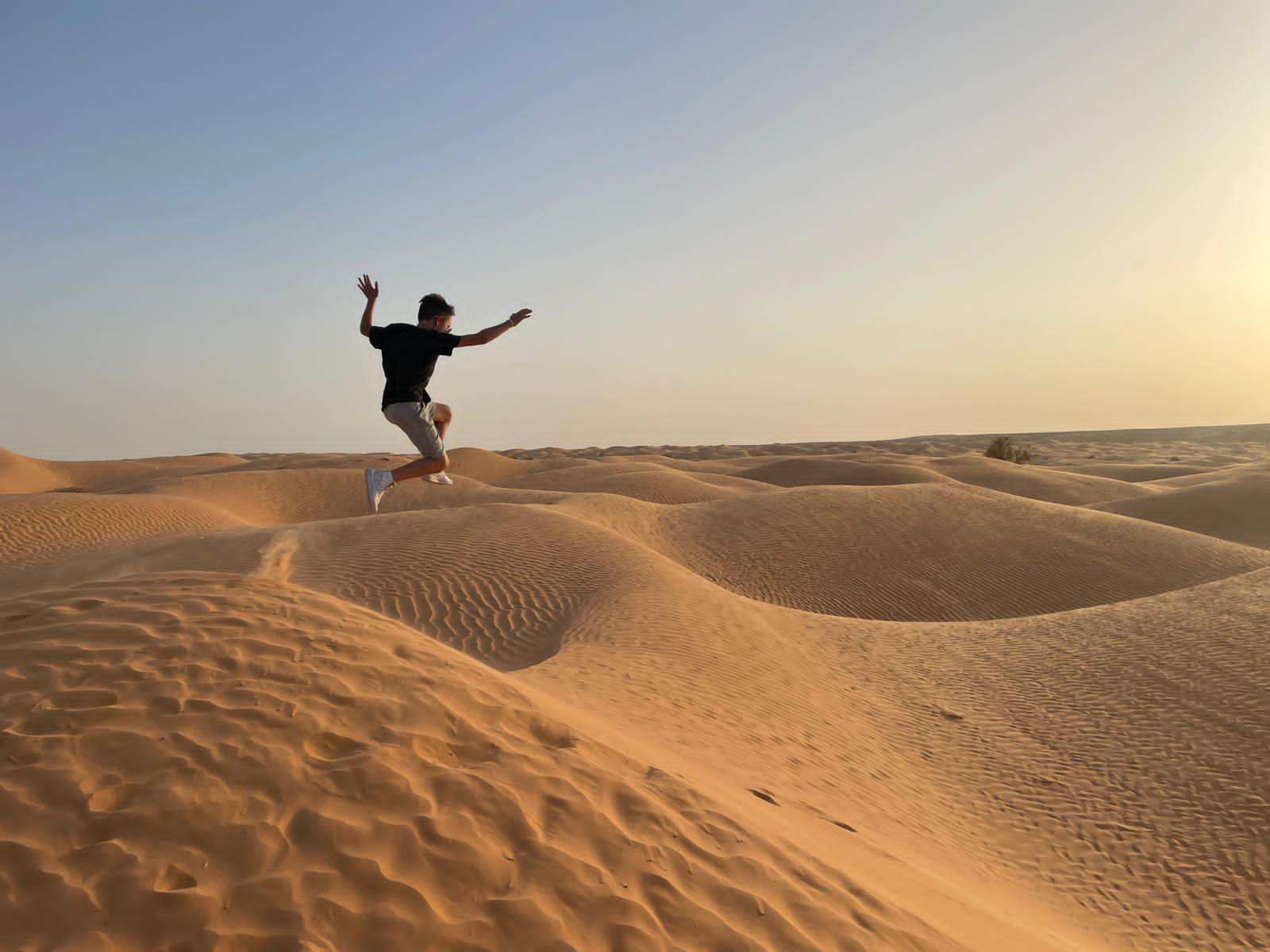 Family walking along a sandy beach at sunset on the island of Djerba in southern Tunisia, with calm sea and warm golden light
