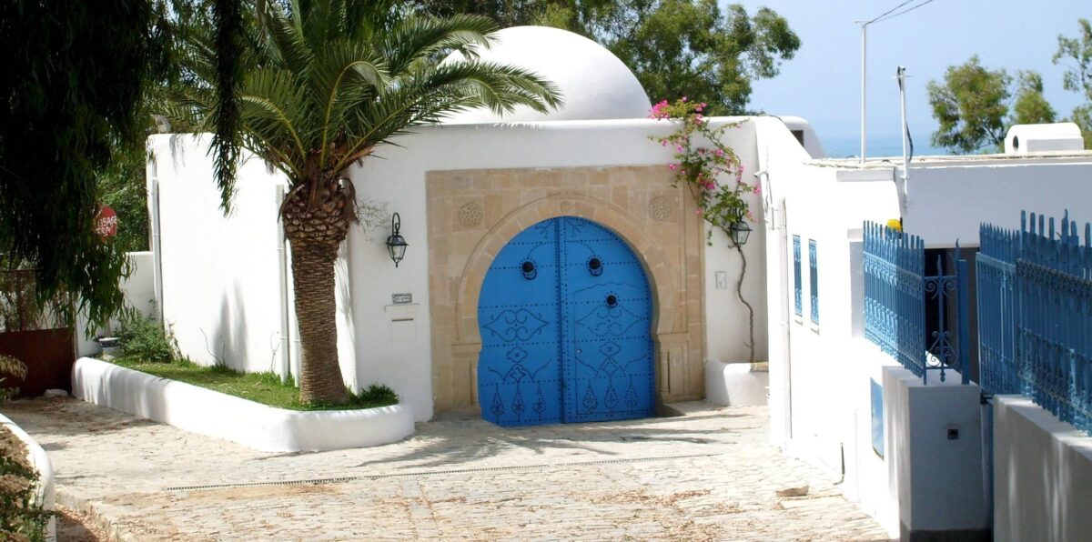 Family walking along the sandy beach of Hammamet at sunset with calm sea and palm-lined waterfront in Tunisia