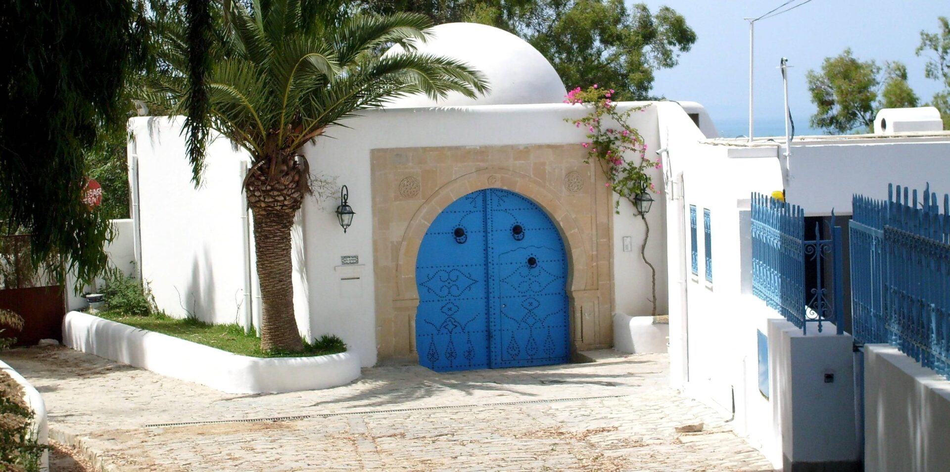Family walking along the sandy beach of Hammamet at sunset with calm sea and palm-lined waterfront in Tunisia