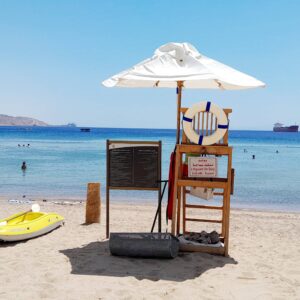 Family walking through the red rock canyon of Petra in Jordan, with sunlight illuminating the carved stone façade in the distance