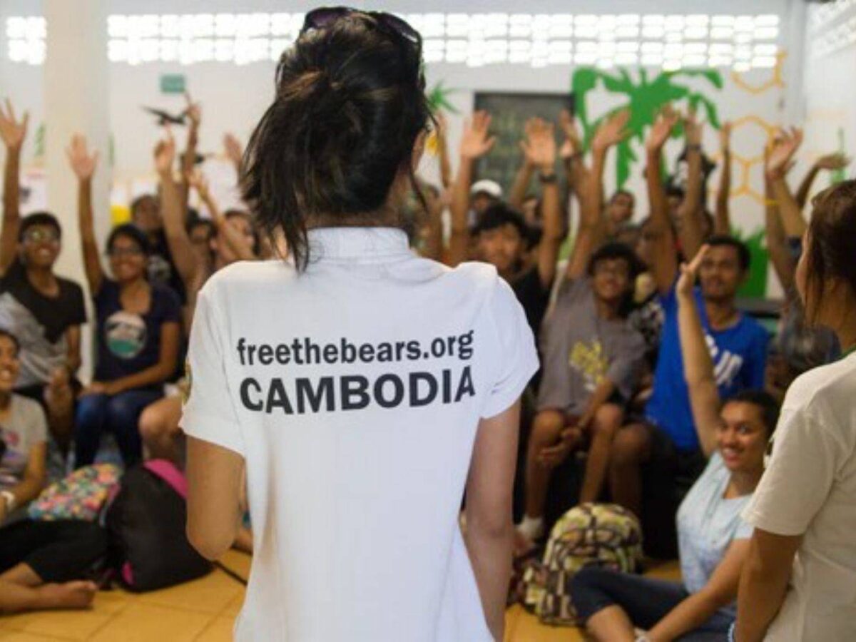 Family watching a rescued sun bear climbing in an enclosure at a wildlife sanctuary near Phnom Penh