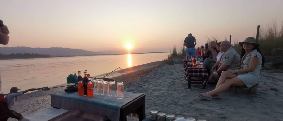 Grassy riverbank on the edge of Chitwan National Park with jungle vegetation and hazy hills at sunset