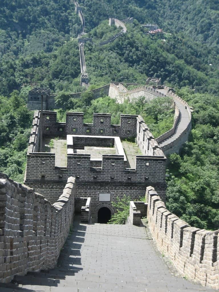 Great Wall of China winding over green hills near Mutianyu under a clear blue sky