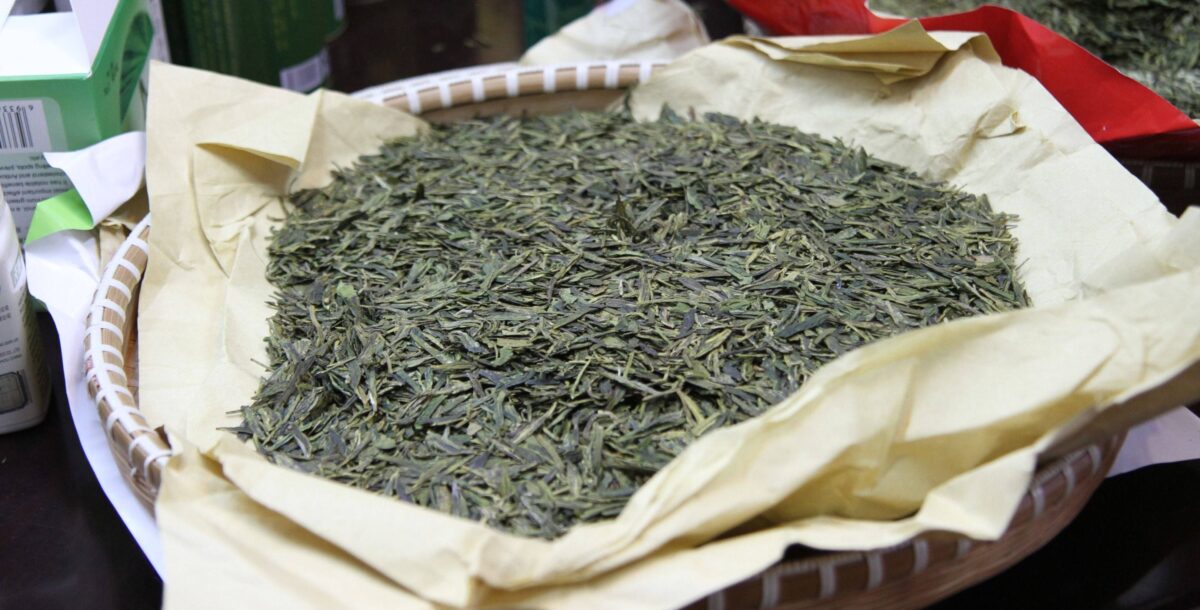 Green terraced tea fields around Longjing village near Hangzhou with misty hills in the background
