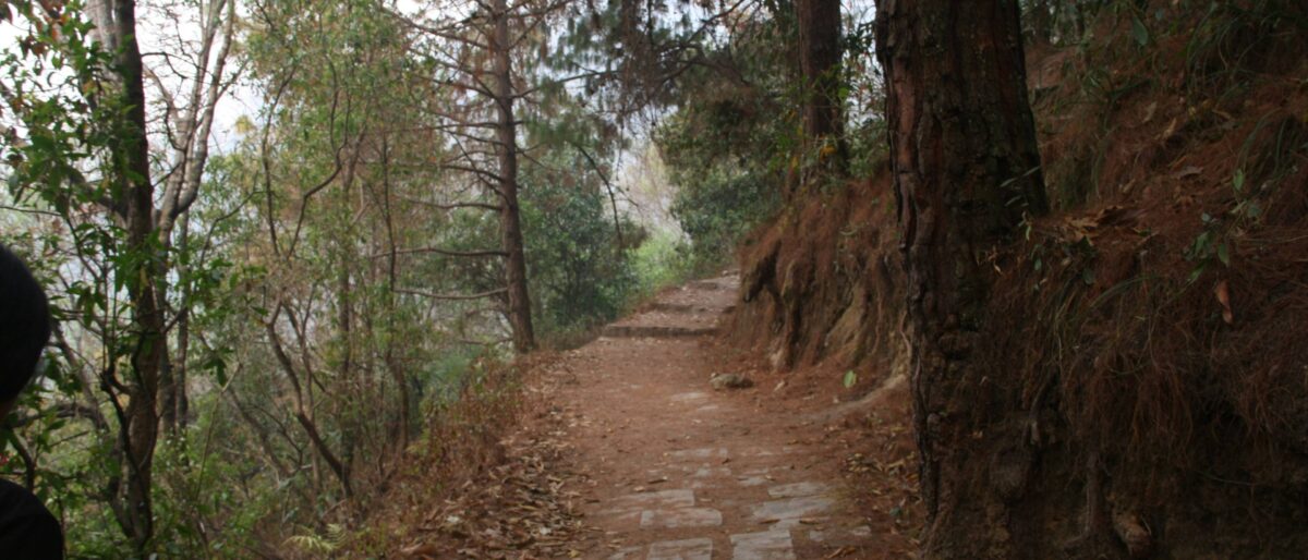 Hiker on a ridge trail at Lakhuri Bhanjyang with panoramic views of distant snow-capped Himalayan mountains