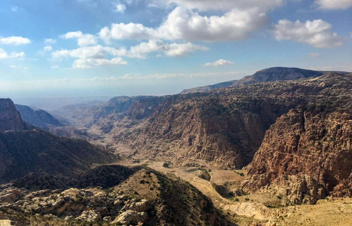 Hikers walking along a trail overlooking the rugged canyons and cliffs of Dana Nature Reserve