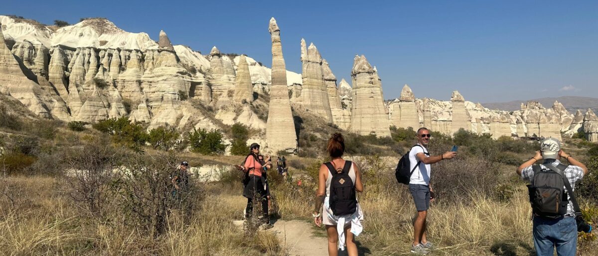 Hikers walking among fairy chimneys and rock-cut churches in Göreme National Park in Cappadocia