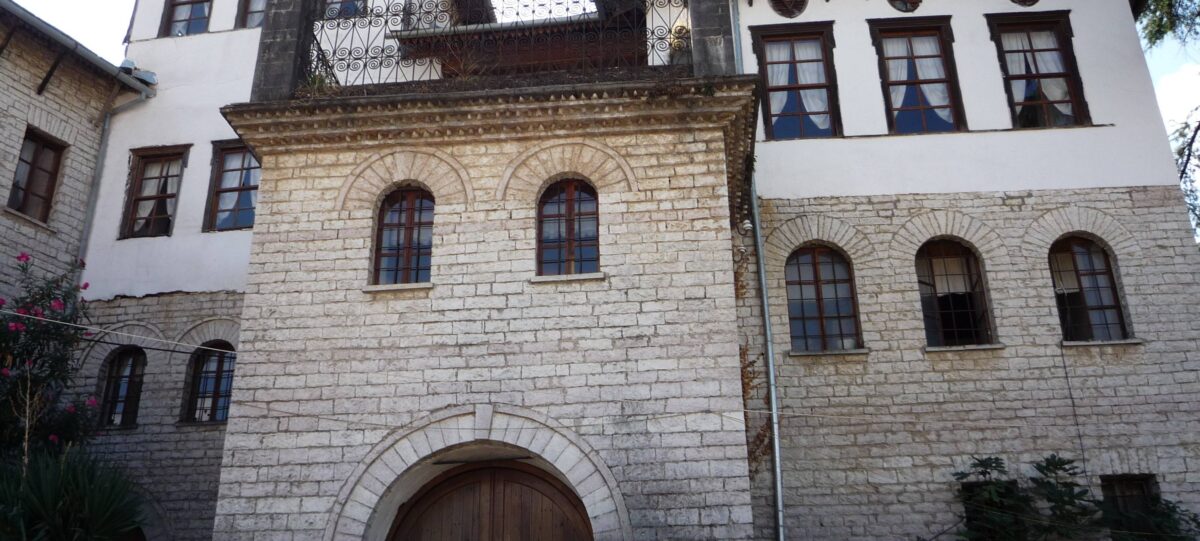 Historic stone houses on a steep hillside in Gjirokastër with the fortress overlooking a wide valley in southern Albania