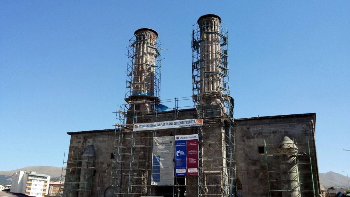 Historic stone madrasa with twin minarets in Erzurum under a blue sky