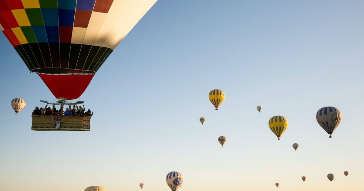 Hot air balloons floating above Cappadocia’s fairy chimney formations at sunrise