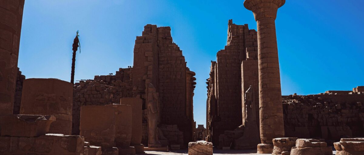 Illuminated Luxor Temple at dusk with towering columns and statues reflected in calm water