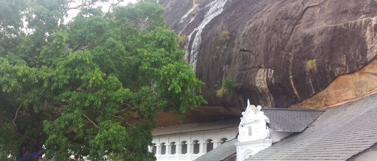 Interior of a Dambulla cave temple in Sri Lanka with golden Buddha statues and colourful Buddhist murals on the rock ceiling