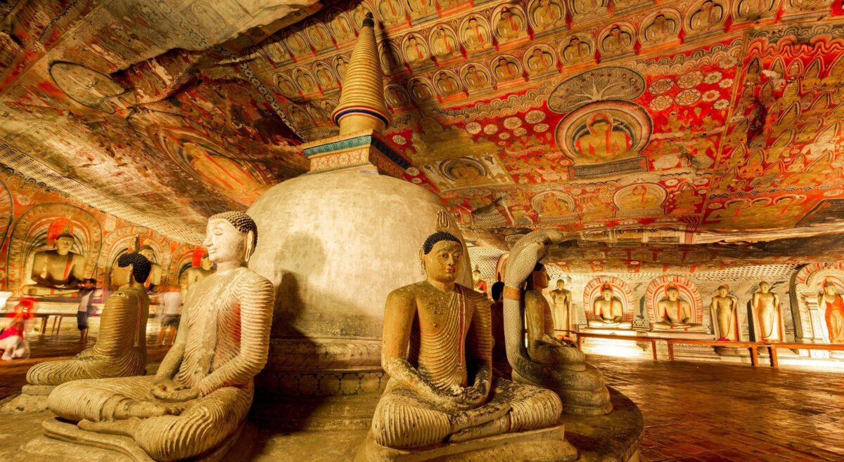 Interior of a Dambulla cave temple with golden Buddha statues and vivid ceiling frescoes