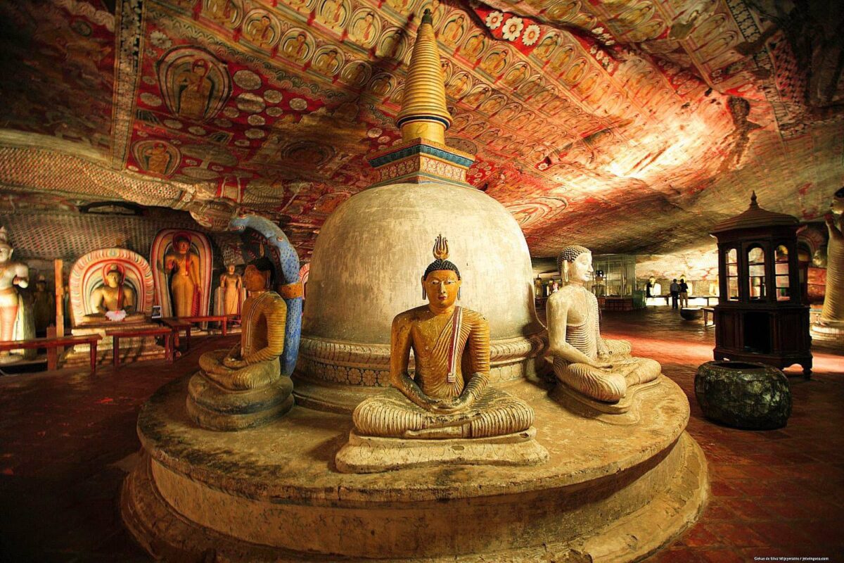 Interior of Dambulla cave temple with golden Buddha statues and colorful painted ceilings in Sri Lanka