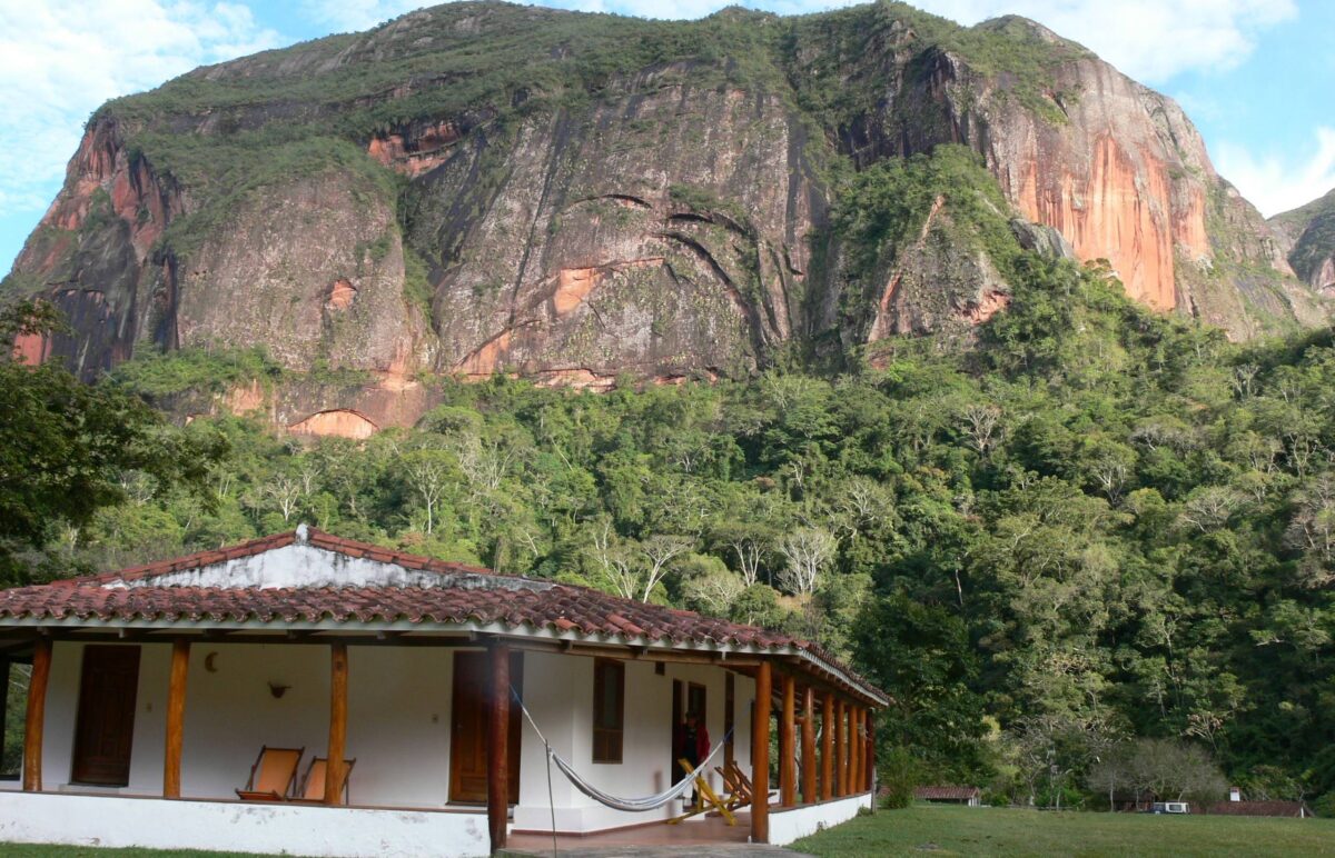 Jungle lodge of Refugio Los Volcanes nestled among red sandstone cliffs and dense subtropical forest in Bolivia