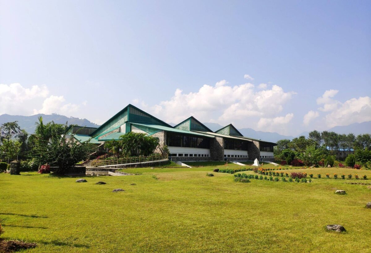 Local Gurung people in traditional dress in Ghandruk village with hills and houses behind them